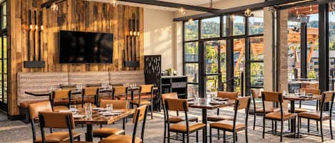 Un comedor moderno con paneles de madera, un televisor de pantalla plana y ventanas amplias que ofrecen vistas al exterior.