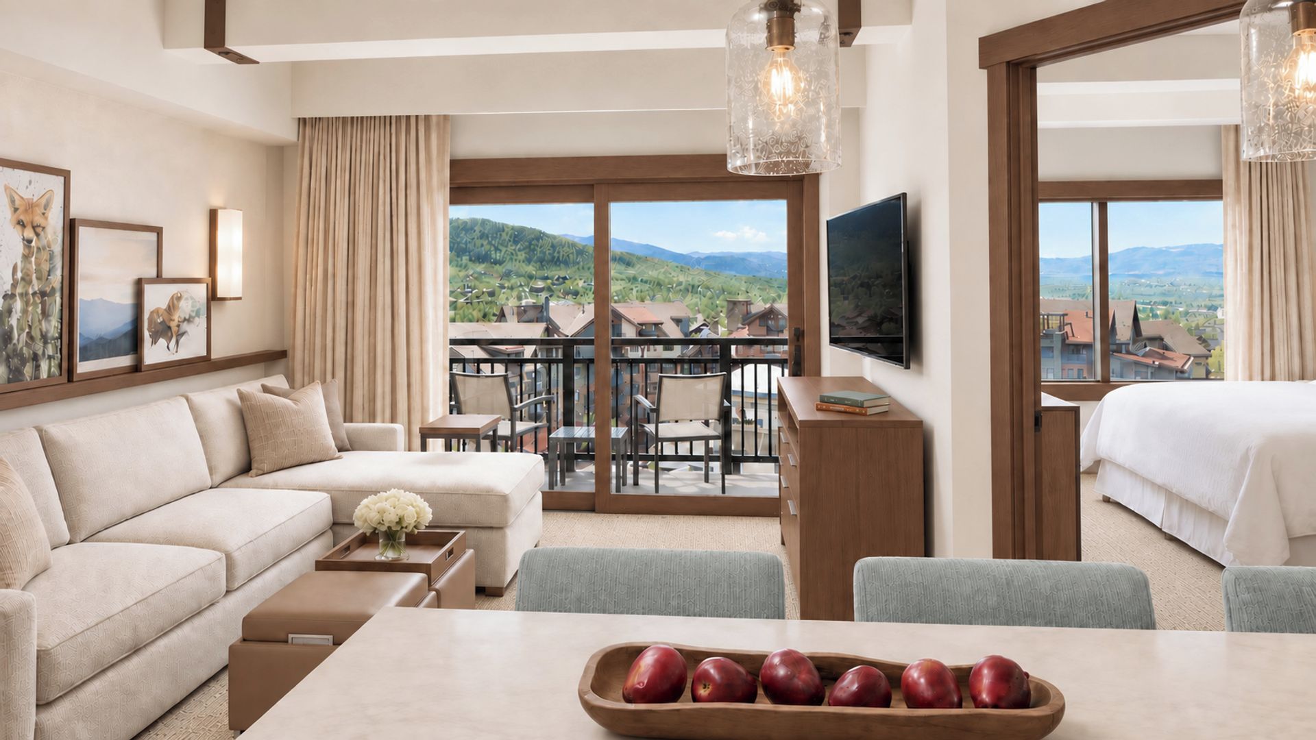 Ein Hotelzimmer mit Balkon, einer Couch, einem Esstisch und einem Fernseher.