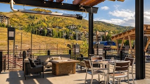 An outdoor terrace with seating, a view of a mountainous landscape, and a restaurant in the background. - TRUE SKI-IN/SKI-OUT Steamboat Springs Resort Villa + Resort Amenities Included (Steamboat Springs)