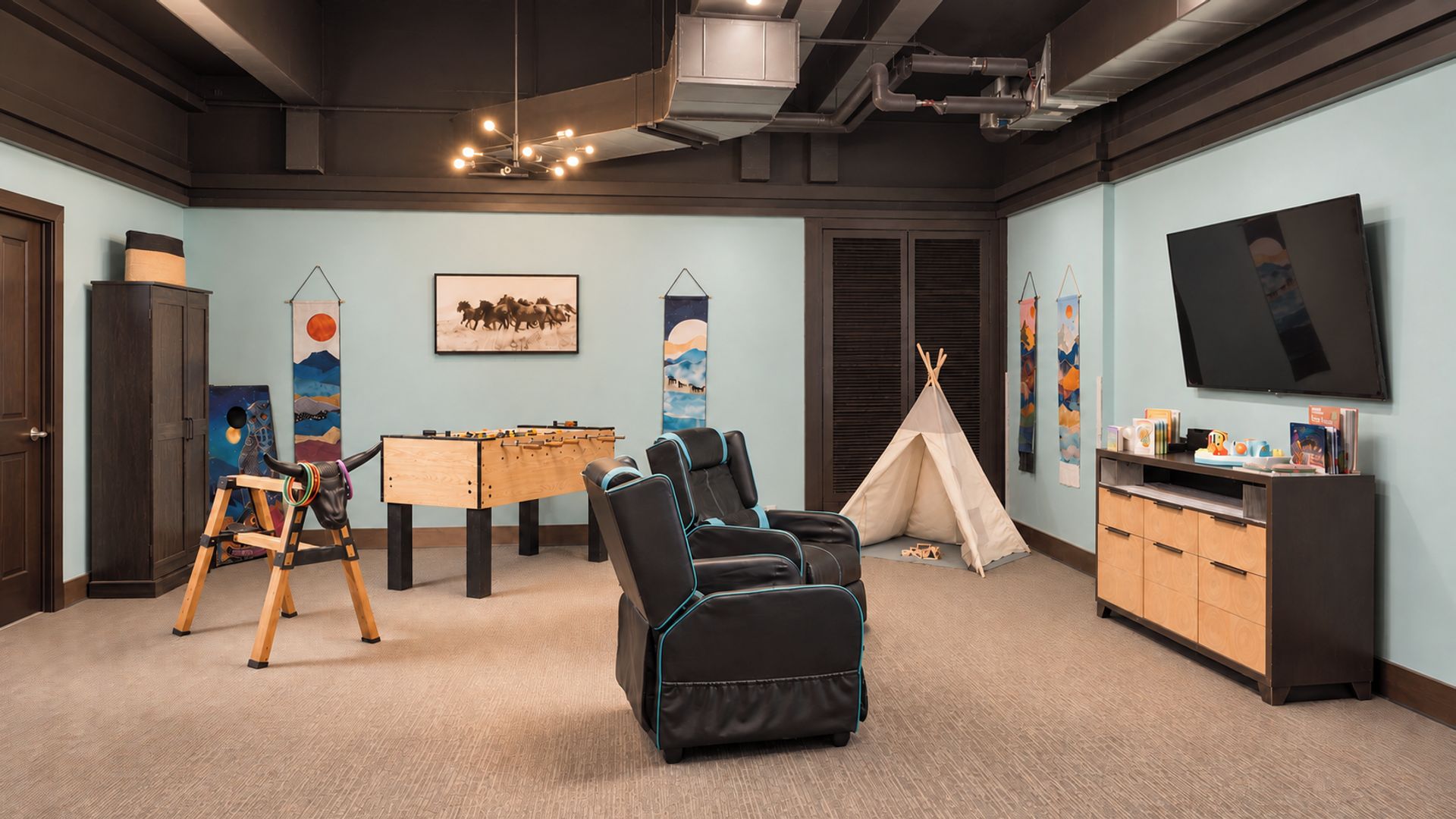 Une pièce équipée d’un baby-foot, de fauteuils massants, d’une tente et d’un téléviseur.