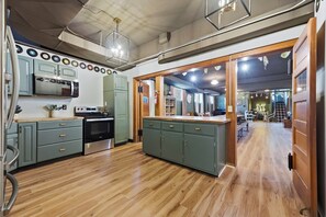 A kitchen with modern appliances, a dining area with a view, and a hallway leading to a living space.