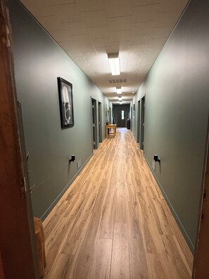 En hall med trägolv, ljusgröna väggar och inramade konstverk på väggarna.