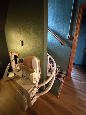 Ett handikappanpassat badrum med trägolv, en grön vägg och ett trähandtag.