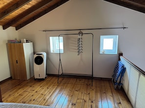 A room with wooden flooring, a ceiling fan, a radiator, a small window, and a wall-mounted drying rack. - Mountain View Village House- Agios Mattheos (Agios Mattheos - Corfu)