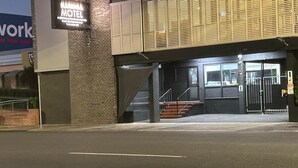 A motel with a brick facade, a signboard, and a gated entrance.