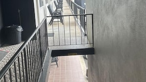 A corridor with a staircase leading to a balcony with seating.