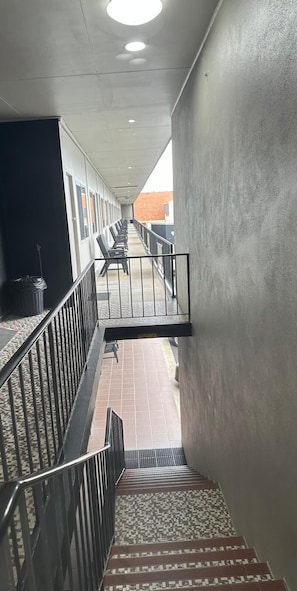 A corridor with a staircase leading to a balcony with seating.