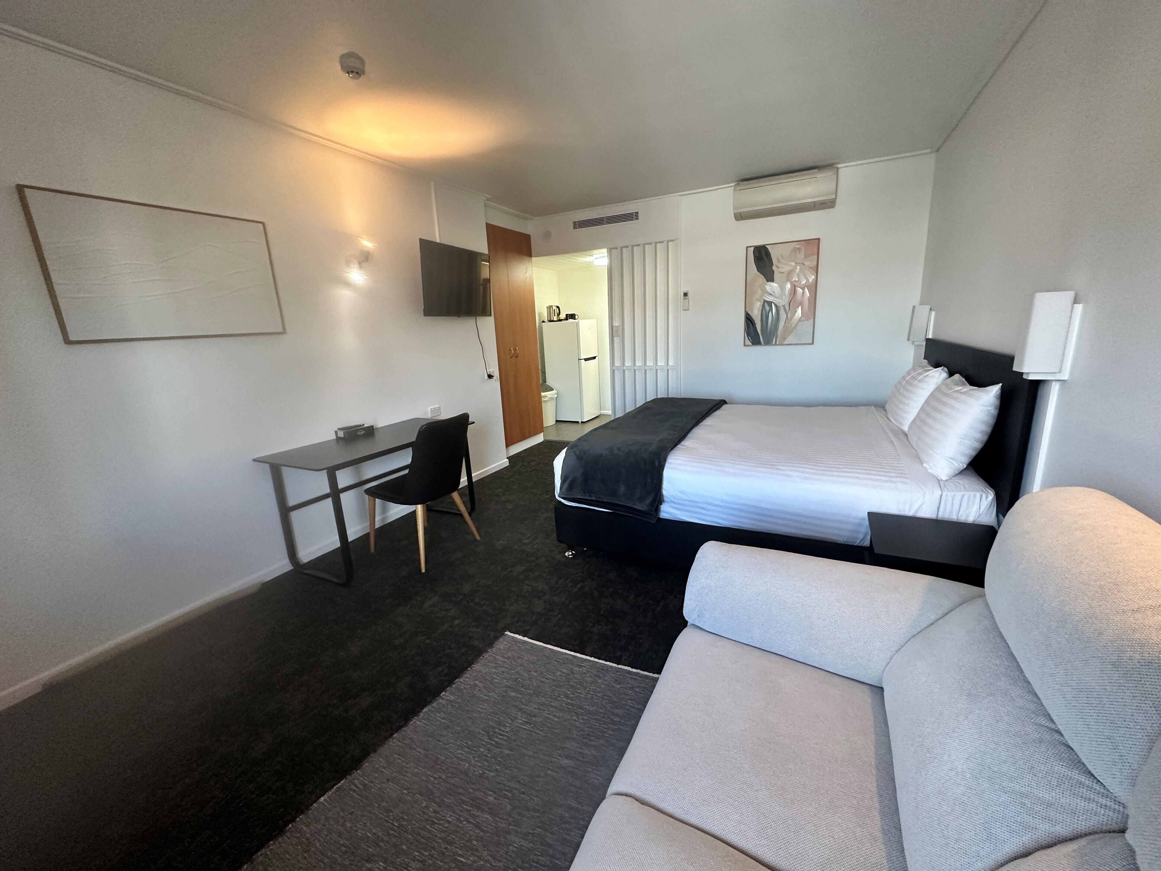 A hotel room with a bed, a desk, a chair, and a couch.
