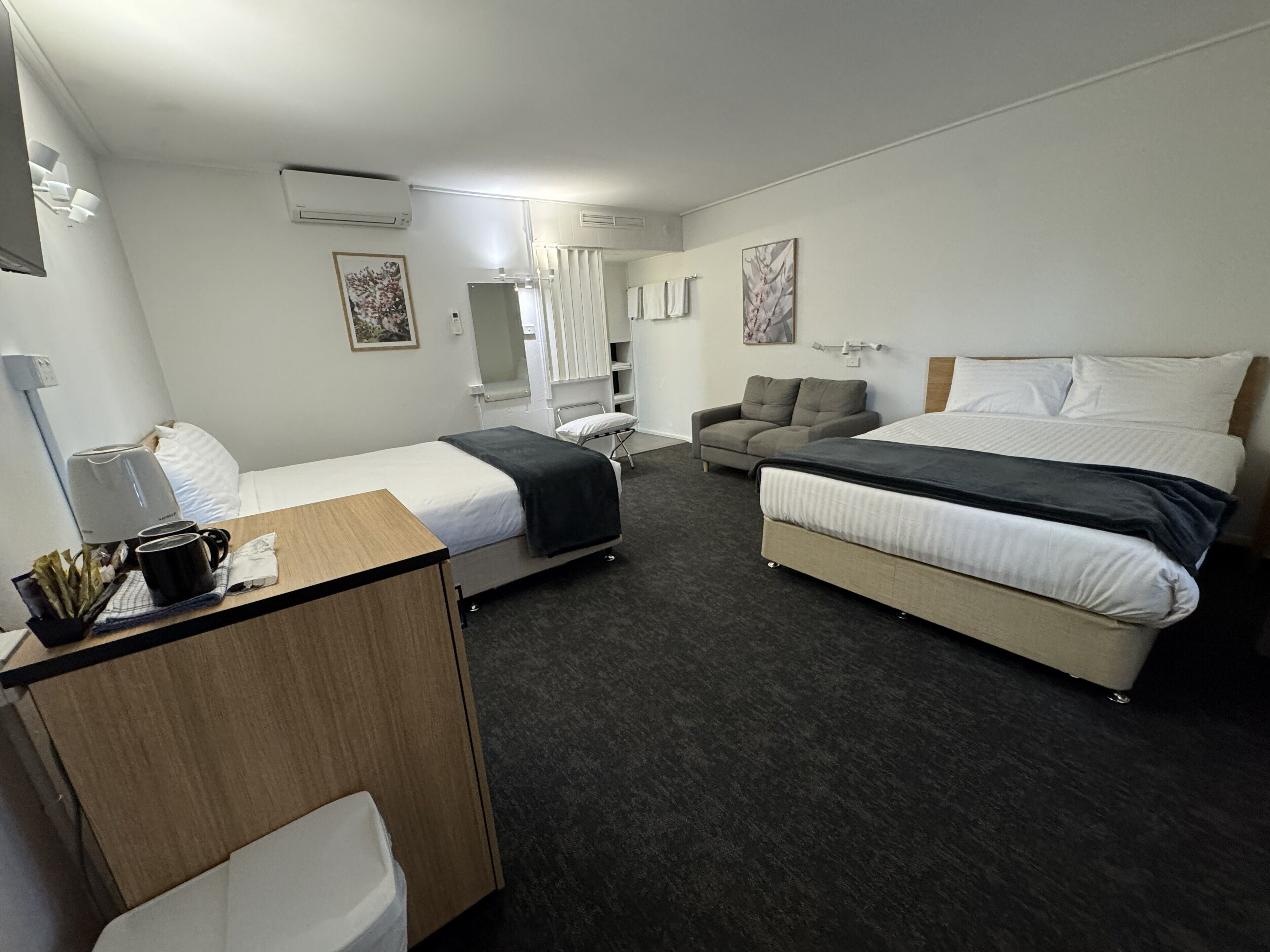 A hotel room with a bed, a sofa, a desk, and a chair.