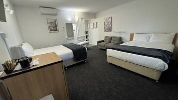 A hotel room with a bed, a sofa, a desk, and a chair.
