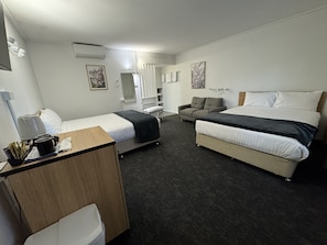 A hotel room with a bed, a sofa, a desk, and a chair.