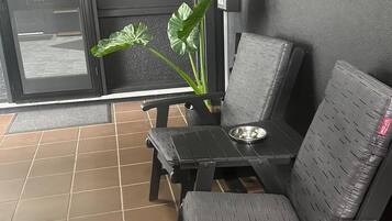 A seating area with two chairs and a table, a potted plant, and a view through a glass door labeled 'OFFICE'.