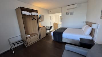 A hotel room with a bed, a wardrobe, a desk, and a chair.