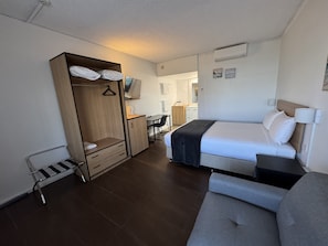 Una habitación de hotel con una cama, un armario, un escritorio y una silla.