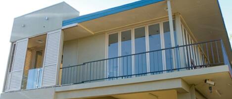 A two-story building with a balcony on the upper floor, large windows, and a flat roof.