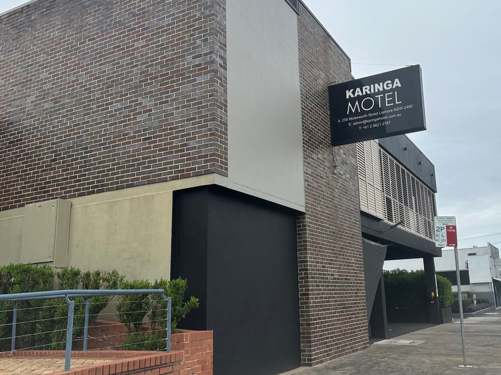A modern building with a sign for Karinga Motel, featuring a brick facade and a flat roof.