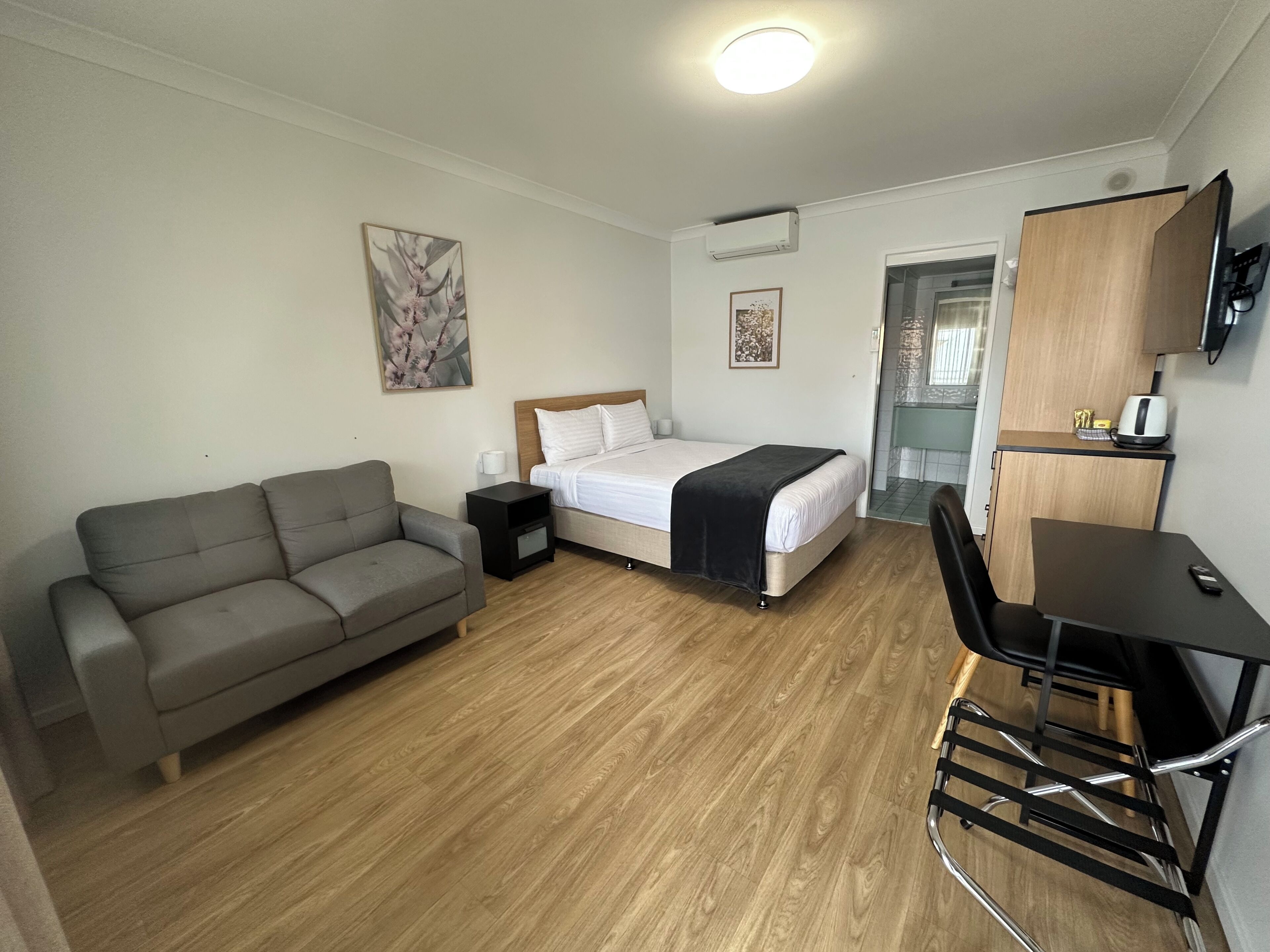 Une chambre d’hôtel de taille réduite, comprenant un lit, un canapé, un bureau et un téléviseur.
