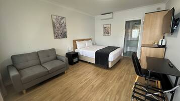Une chambre d’hôtel de taille réduite, comprenant un lit, un canapé, un bureau et un téléviseur.