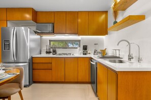 A modern kitchen with wooden cabinets, stainless steel appliances, and a built-in window. - 2BR condo in La Cruz with pool, balcony, AC, WiFi & kitchen. (Bahia de Banderas)