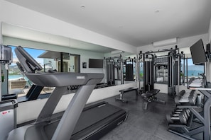 A modern gym with a treadmill, weight machines, and a bench. - 2BR condo in La Cruz with pool, balcony, AC, WiFi & kitchen. (Bahia de Banderas)