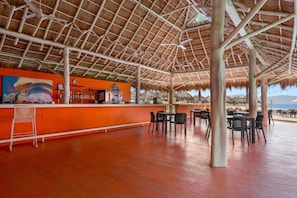 An outdoor bar area with a thatched roof, seating arrangements, and a view of the beach. - 2BR condo in La Cruz with pool, balcony, AC, WiFi & kitchen. (Bahia de Banderas)