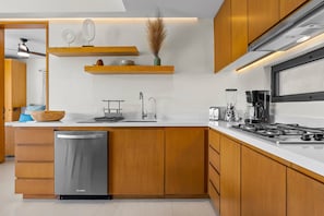 A modern kitchen with wooden cabinets, a stainless steel dishwasher, a gas stove, and a built-in oven. - 2BR Modern Condo, Marina View, Rooftop Pool & Beach Club, Sleeps 6 (Bahia de Banderas)