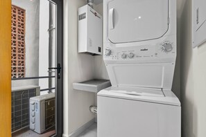 Ein kleiner Hauswirtschaftsraum mit einer Waschmaschine mit Frontlader, einem Trockner und einer kleinen Arbeitsplatte.