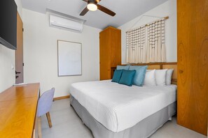A bedroom with a bed, a desk, a chair, a ceiling fan, an air conditioner, and a wall-mounted decorative piece. - 2BR Modern Condo, Marina View, Rooftop Pool & Beach Club, Sleeps 6 (Bahia de Banderas)