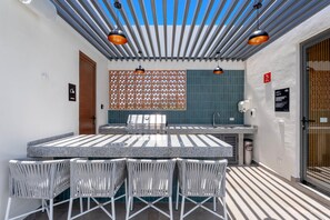 Un patio al aire libre con mesa y sillas, una parrilla y un techo con diseño.