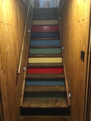 Eine Holztreppe mit abwechselnd farbig gestalteten Stufen.
