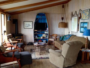 Ein gemütliches Wohnzimmer mit Kamin, Fernseher und Bücherregal.