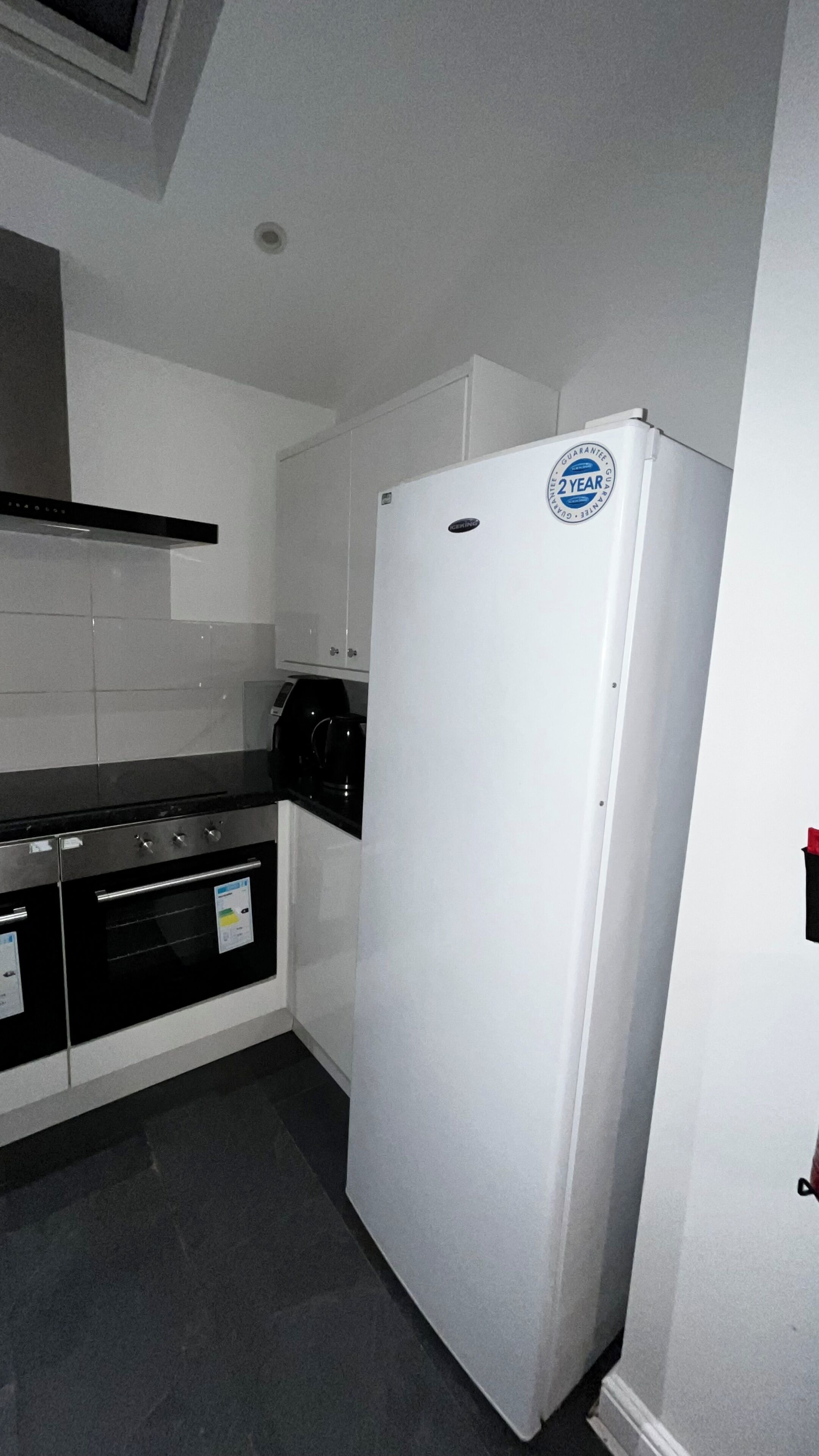 A compact kitchen with a white refrigerator, a stove, and a coffee maker.