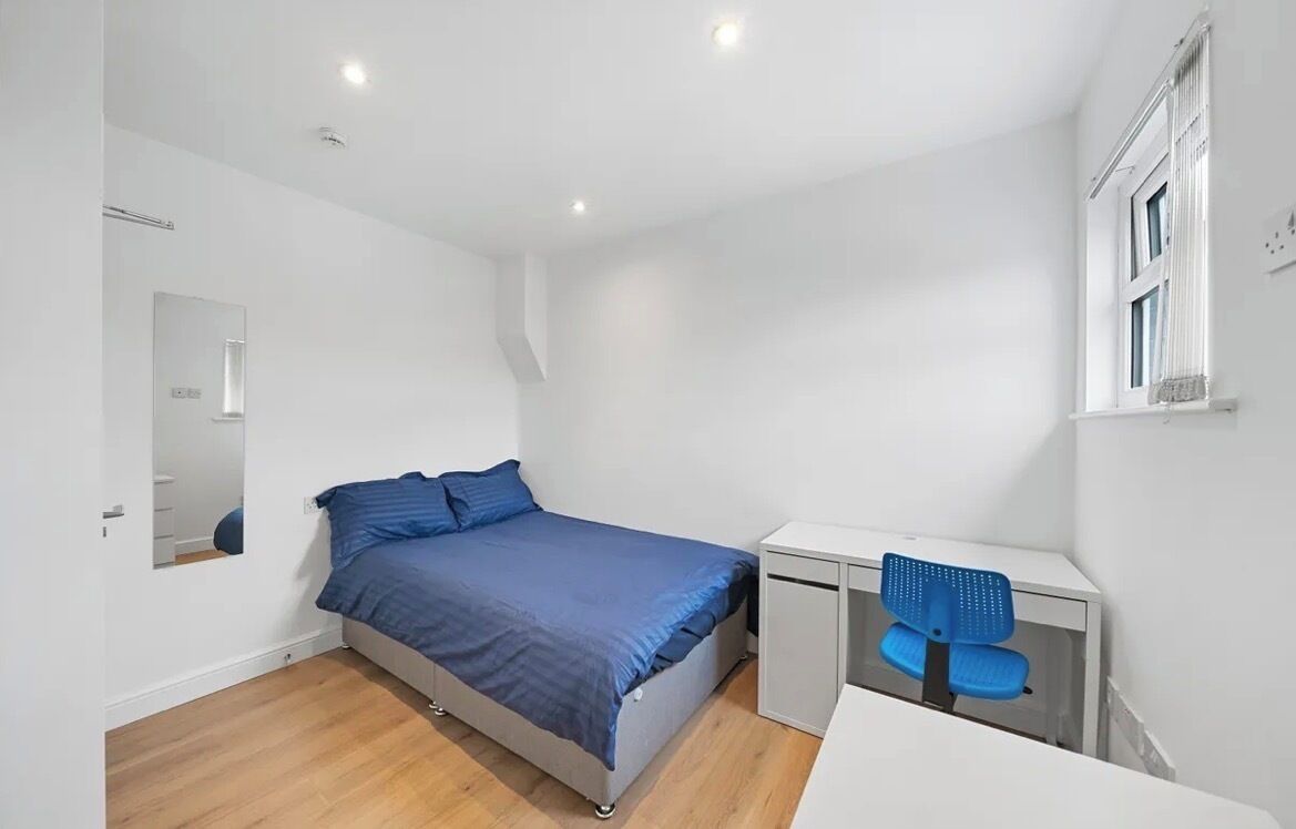 A bedroom with a bed, a desk, and a chair.