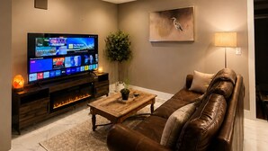 Ein modernes Wohnzimmer mit Flachbildfernseher, Ledersofa und einem dekorativen Gemälde.
