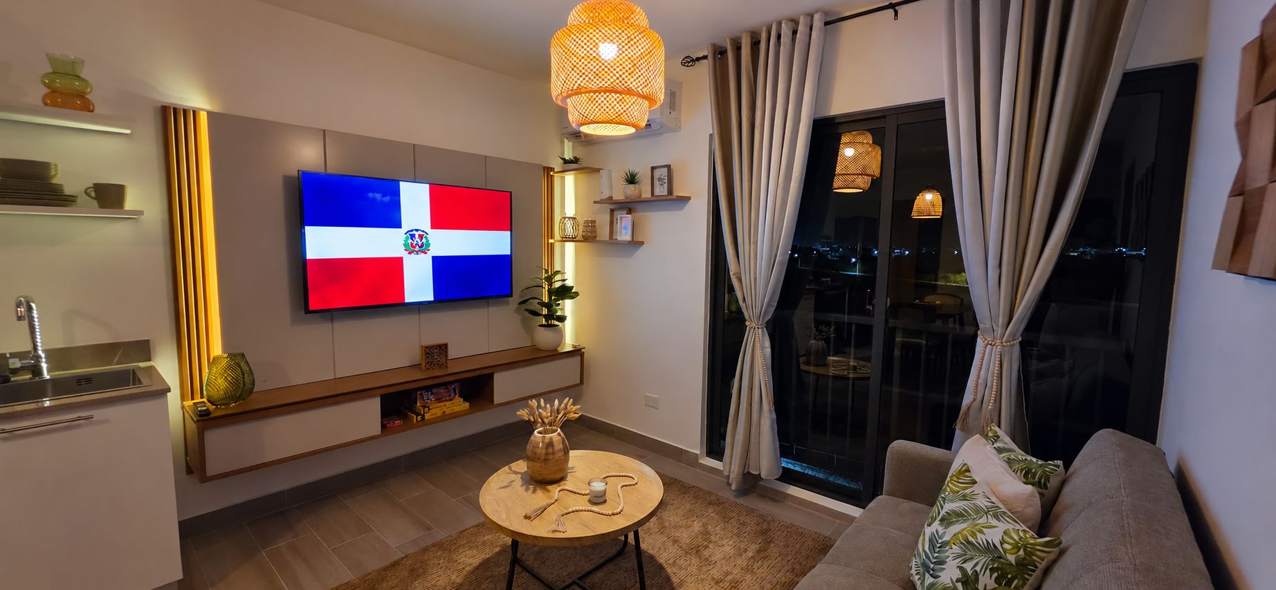 Un salon moderne doté d’un téléviseur à écran plat, d’un coin repas avec une table ronde et d’un canapé agrémenté de coussins.