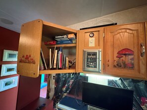 Un mueble de madera con un reloj, un televisor Sony y varios objetos, entre ellos libros y una caja de juegos.