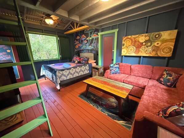 Una habitación con una cama doble, un sofá, una mesita de centro y un cuadro en la pared.