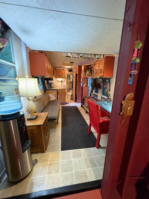A compact kitchen with a water dispenser, a stove, and a refrigerator.