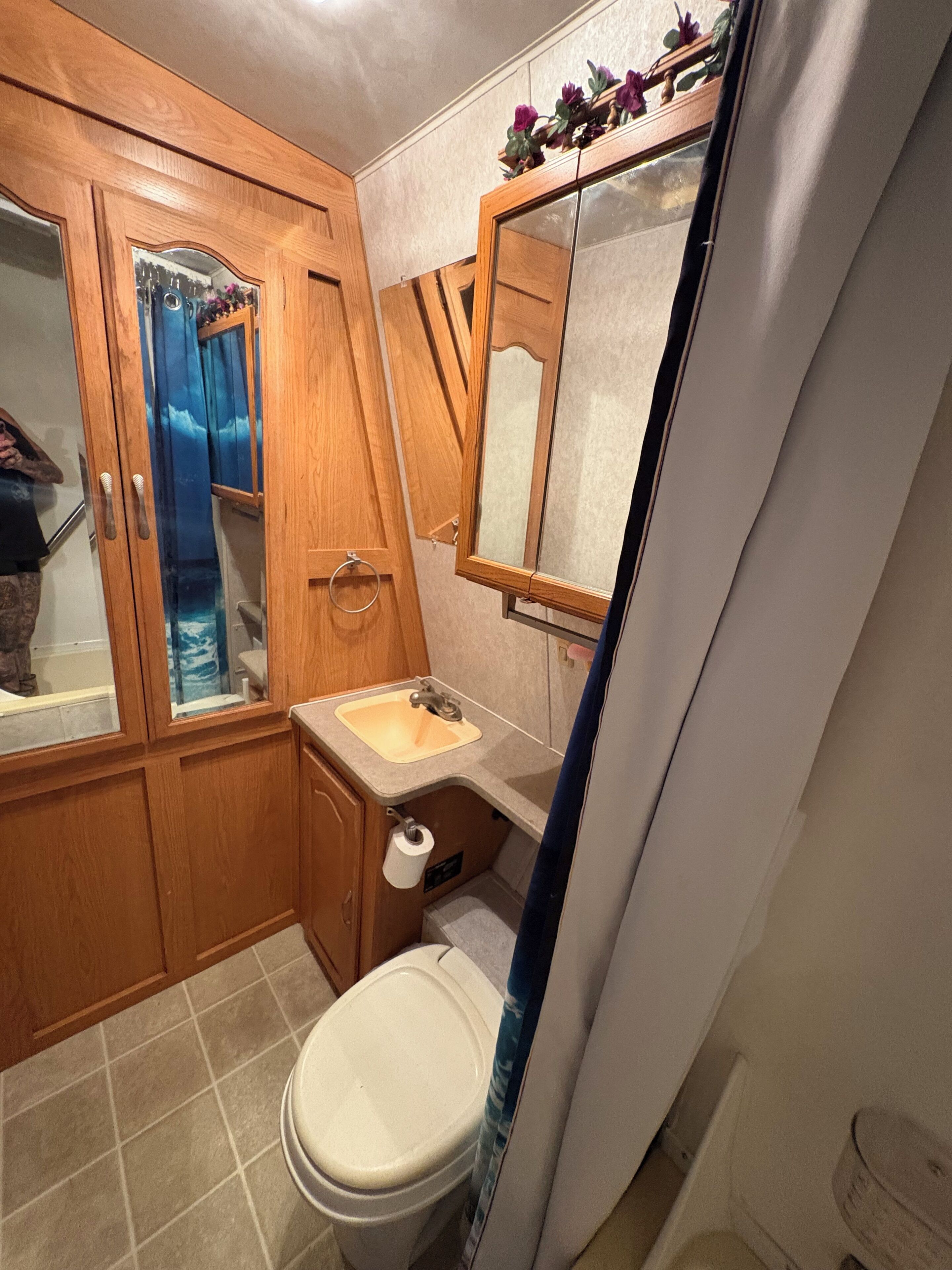 A bathroom with a wooden vanity, a sink, a toilet, and a mirror.