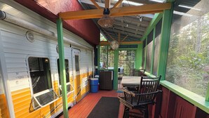 Uma área externa coberta com um deck de madeira, um banco e uma mesa.