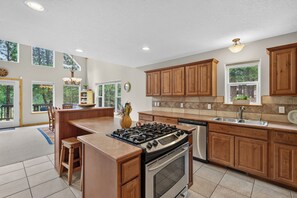 A spacious kitchen with wooden cabinets, a gas stove, a dishwasher, and a large island. - Home with access to the Elk Trail (Angel Fire)