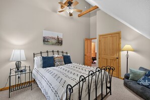 A bedroom with a bed, bedside lamps, a painting, a door, and a ceiling fan. - Home with access to the Elk Trail (Angel Fire)