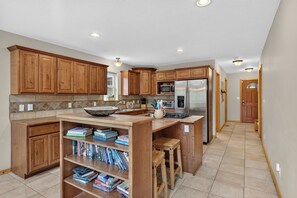 A modern kitchen with wooden cabinets, a built-in island, and a stainless steel refrigerator. - Home with access to the Elk Trail (Angel Fire)
