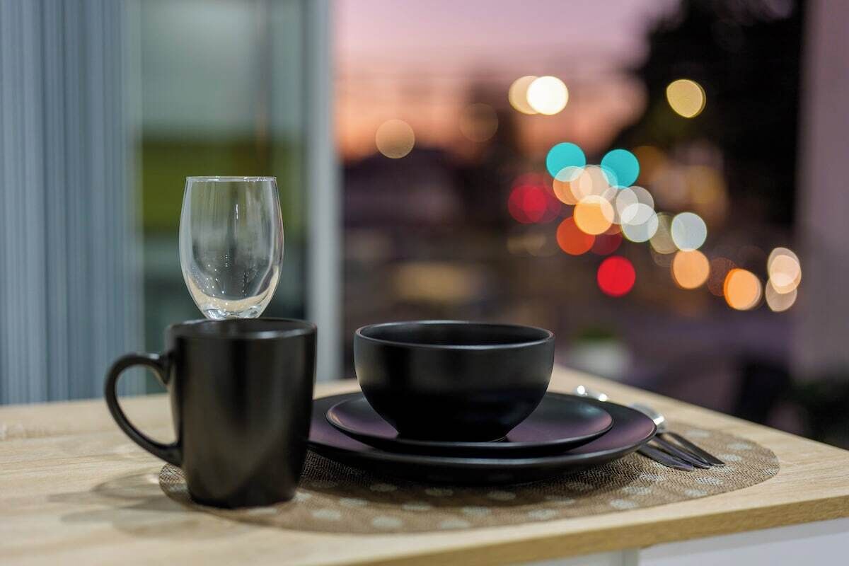 A table with a black mug, a black bowl, and a plate, set on a placemat.