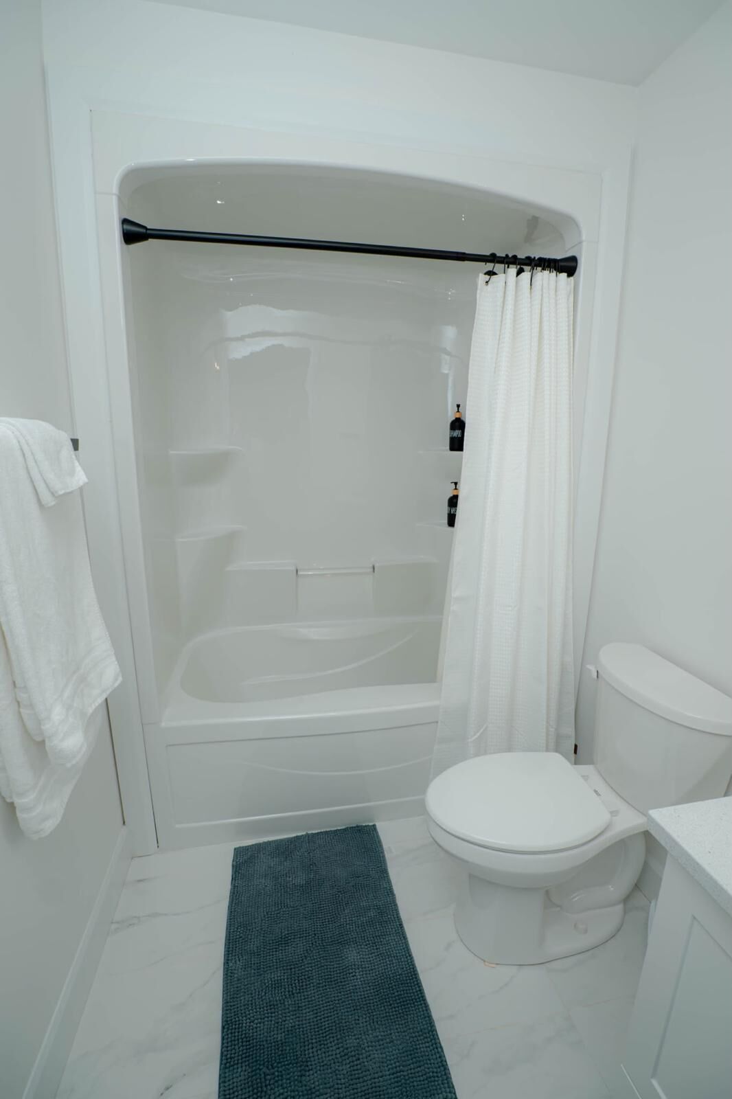 A bathroom with a bathtub, toilet, and a green rug.
