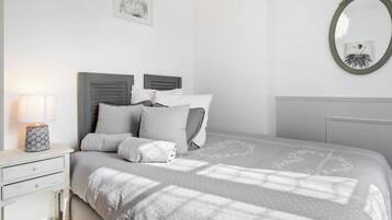 Una camera da letto con un letto, un comodino, una lampada, uno specchio e un quadro appeso al muro.