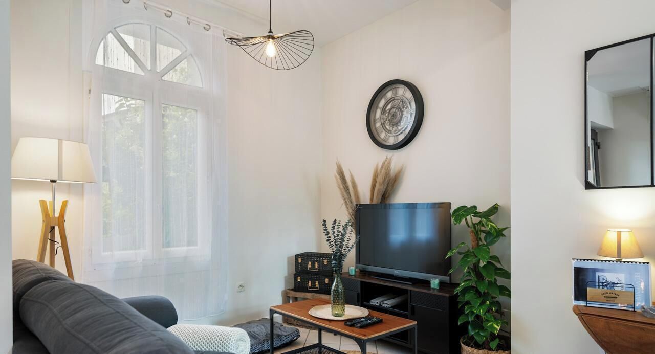 A living room with a sofa, a coffee table, a TV, and a plant.