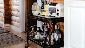 A wooden cabin interior with a kitchen area featuring a toaster, a blender, and a cart with bottles. - Traditional cabin among the dunes (Skagen)
