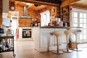 A cozy kitchen with wooden beams, a central island with bar stools, and a refrigerator. - Traditional cabin among the dunes (Skagen)