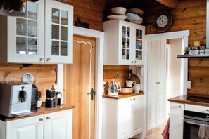 Cocina con gabinetes blancos, una cafetera y encimeras de madera.
